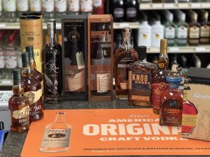 Bottles of whiskey and bourbon displayed on a counter, with a Tito’s Vodka mat in the foreground.