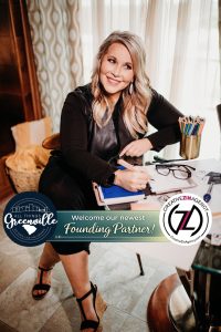 Smiling woman sits at desk with art supplies, welcoming her as the newest founding partner for a creative agency.