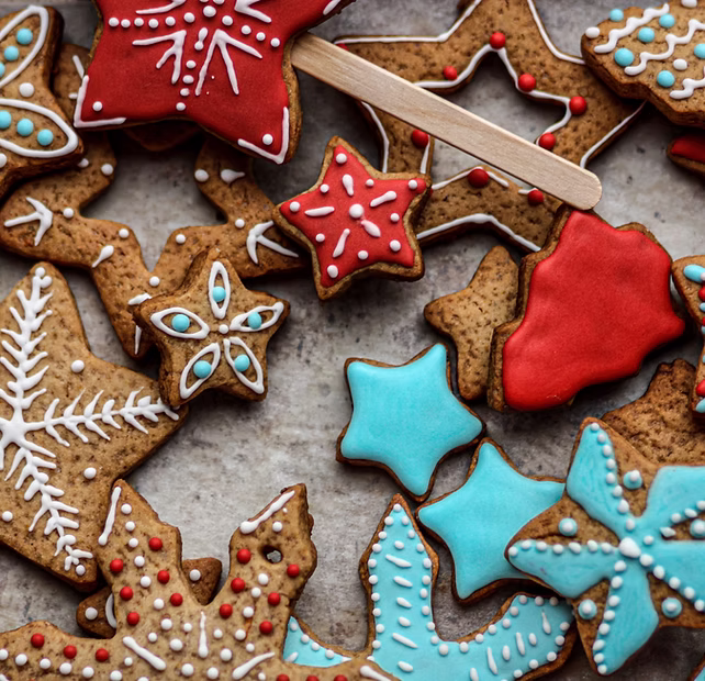 Assorted decorated holiday cookies in red, white, and blue icing, shaped like stars and snowflakes.