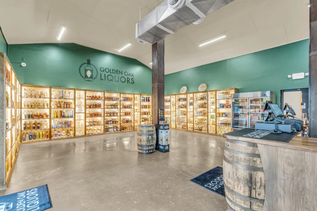 Interior of Golden Oak Liquors with shelves of bottles, wooden barrels, and a register counter.