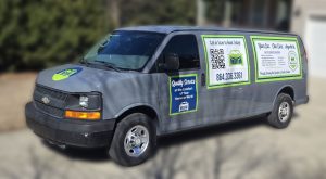 Gray service van with green and blue signage, displaying a phone number, QR code, and booking information.