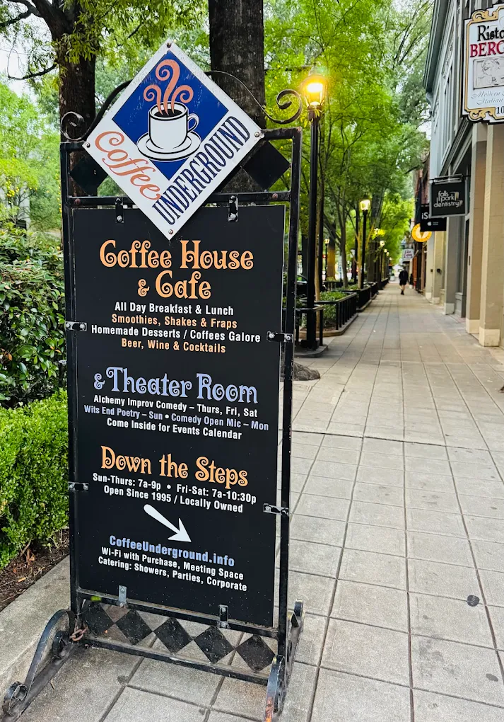 A sidewalk sign for Coffee Underground café listing menu items, theater room details, and contact information.