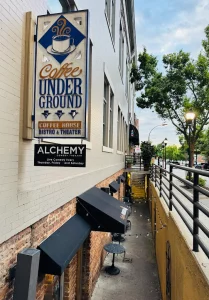 Sign for "Coffee Underground" above stairs leading to a basement entrance, with tables along the walkway.
