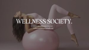 Woman in pink workout clothes lying on a pink exercise ball with “WELLNESS SOCIETY.” text overlay.